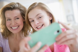 Caucasian mother and daughter taking selfies with cell phone