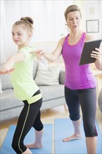 Caucasian mother and daughter practicing yoga with digital tablet
