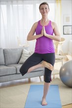 Caucasian woman practicing yoga in living room