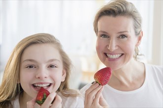 Caucasian mother and daughter eating strawberries