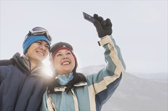 Couple in winter clothing taking selfie near mountain