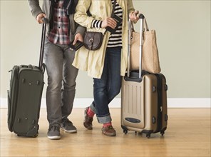 Couple holding rolling luggage in living room