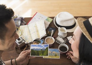Close up of traveling couple admiring photographs at breakfast