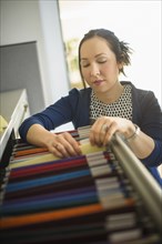 Mixed race businesswoman choosing files in office