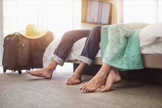 Legs of couple laying on bed in hotel room