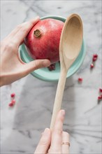 Close up of hands cracking pomegranate with spoon