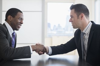 Businessmen shaking hands in office meeting
