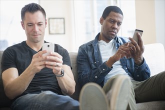 Men using cell phones on sofa