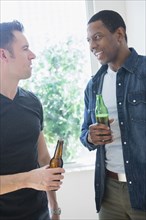 Men drinking beer near window