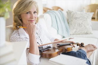 Caucasian woman holding violin on sofa