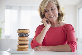 Caucasian woman admiring stack of donuts on table