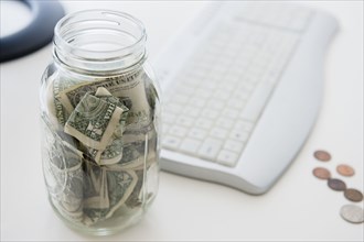 Close up of savings jar near computer keyboard