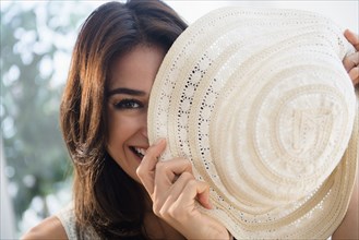Close up of woman hiding behind sun hat