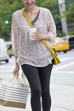 Hispanic woman carrying shopping bag on city sidewalk