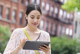 Hispanic woman using digital tablet in city
