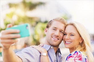 Caucasian couple taking selfie on cell phone