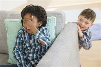 Close up of boys playing hide and seek in living room