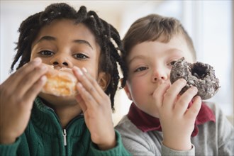 Close up of boys eating donuts