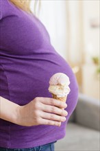 Caucasian pregnant woman holding ice cream cone