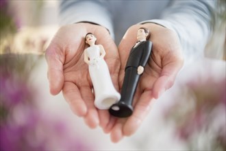 Hands holding bride and groom cake toppers
