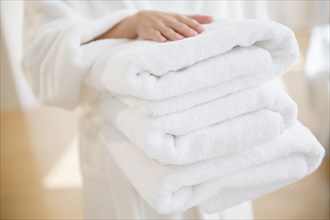 Mixed race woman carrying stack of clean towels