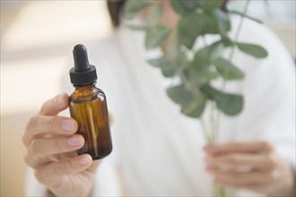 Mixed race woman holding bottle of essential oil