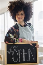 Mixed race woman holding open sign in cafe