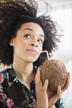 Mixed race woman drinking coconut water with straw