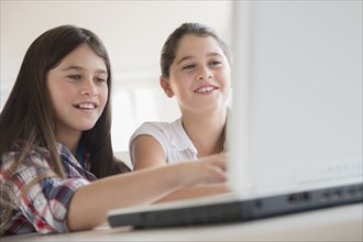 Caucasian twin sisters using laptop