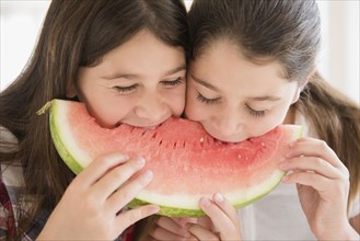 Caucasian twin sisters eating watermelon