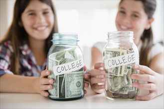 Caucasian twin sisters saving for college