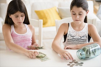 Caucasian twin sisters counting savings