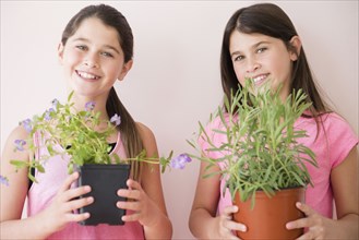 Caucasian twin sisters holding potted plants