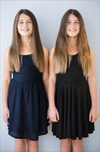 Caucasian twin sisters wearing dresses