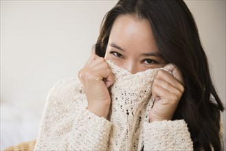 Chinese woman peeking over collar of sweater