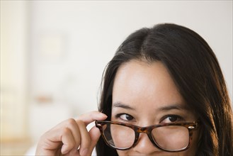 Chinese woman peering over eyeglasses