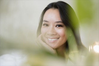 Chinese woman smiling with chin in hand