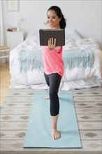 Chinese woman practicing yoga with digital tablet