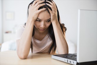 Frustrated Chinese woman using laptop