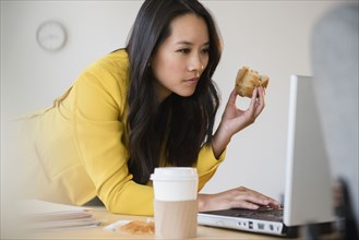 Chinese businesswoman using laptop and eating
