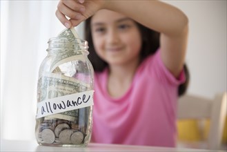 Girl saving allowance in money jar
