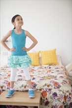 Girl standing on table near bed