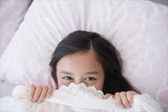 Girl peeking out from bed blankets