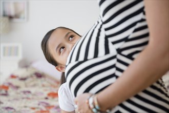 Girl admiring belly of pregnant mother
