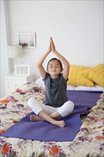 Girl practicing yoga on bed