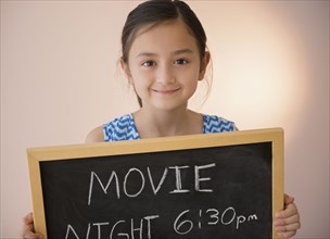 Girl holding chalkboard movie night sign