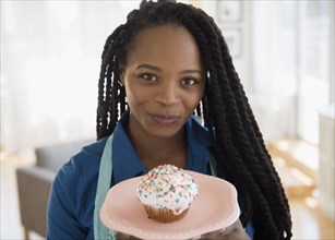 Black woman holding cupcake on plate