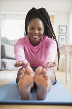 Black woman practicing yoga in living room