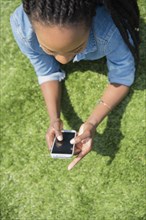 Black woman using cell phone in grass
