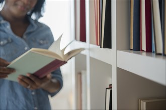 Black woman reading book at bookcase